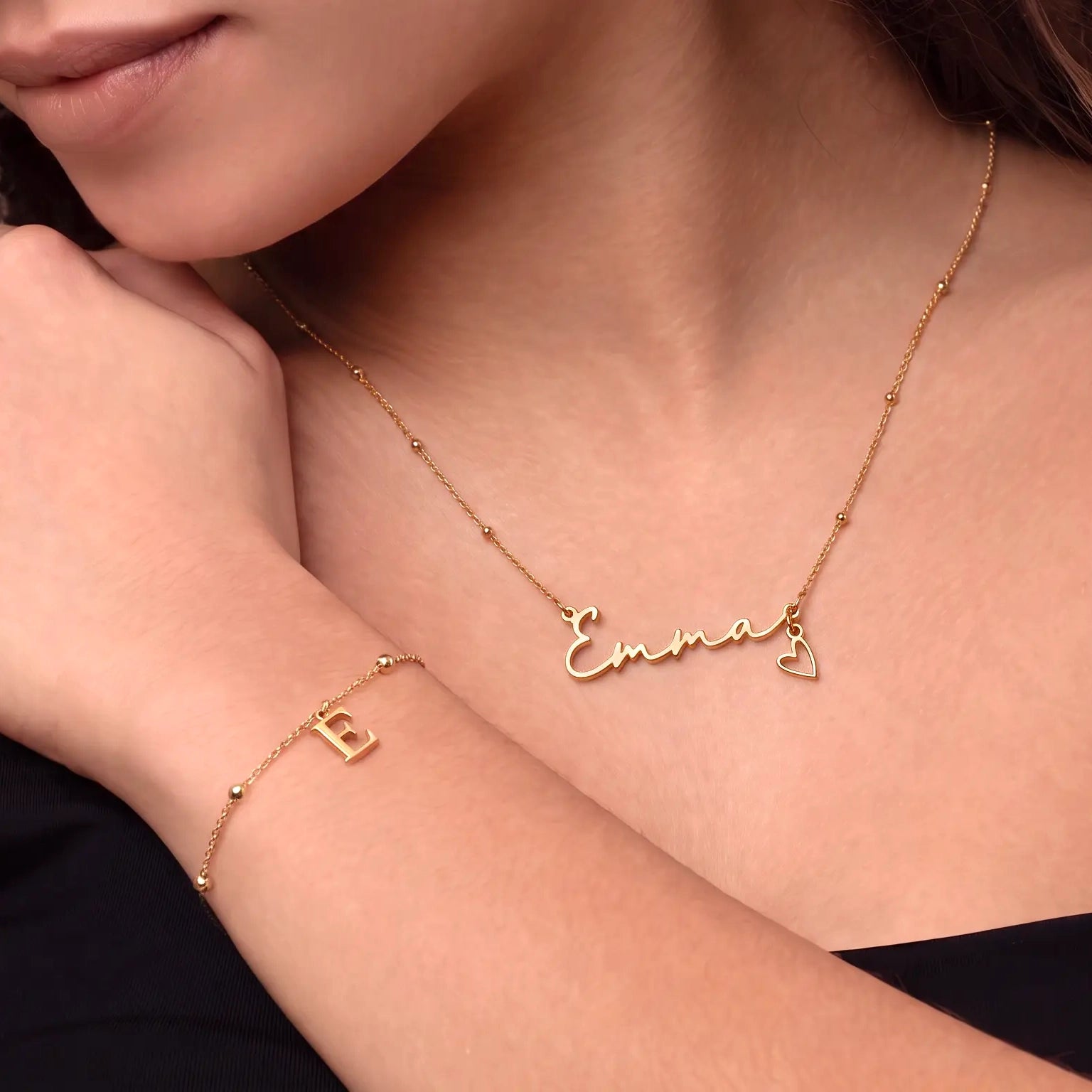 Girl wearing a gold personalised Ella name necklace while holding a teddy bear with a matching Brooke necklace